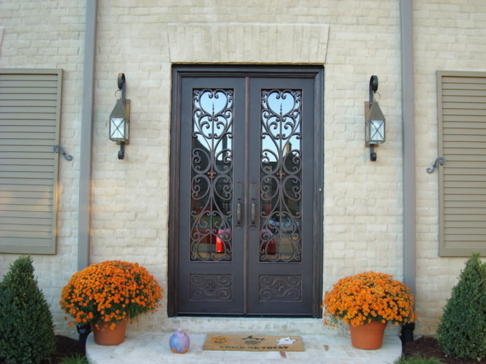 βεράντα εξοχικού σπιτιού με πόρτα εισόδου με σφυρήλατο σίδερο και γυαλί