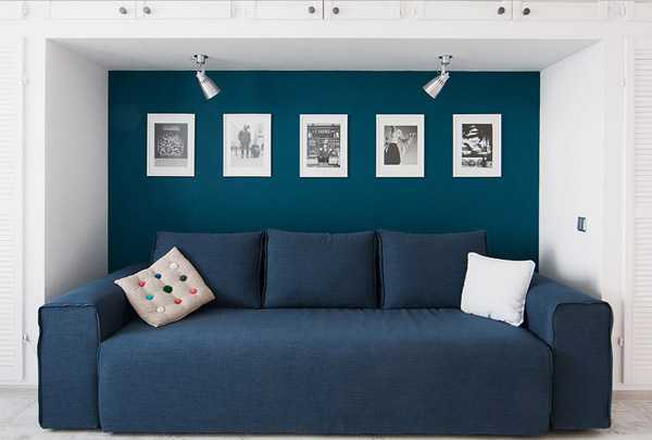 niebieska sofa, ramki na zdjęcia na niebieskiej ścianie