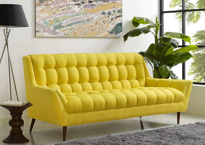 geltona sofa ant kojų interjere